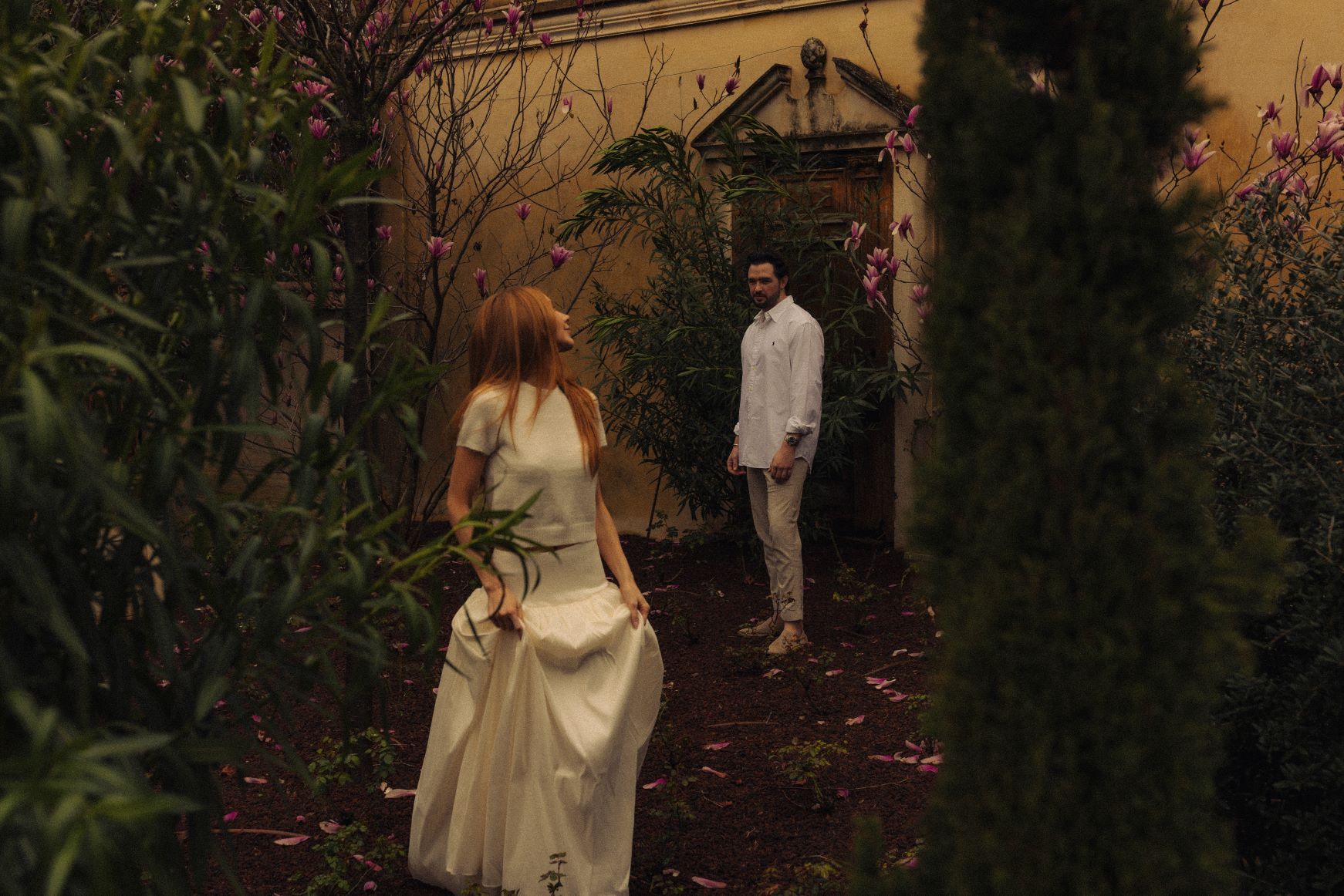 Photo d'un homme en arrière plan et de la femme au premier plan qui regarde en arrière en avançant et en tenant sa jupe